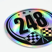 Pair of holographic racing number stickers for cars featuring bold numbers on a shiny rainbow-colored background, by MC Motoparts.